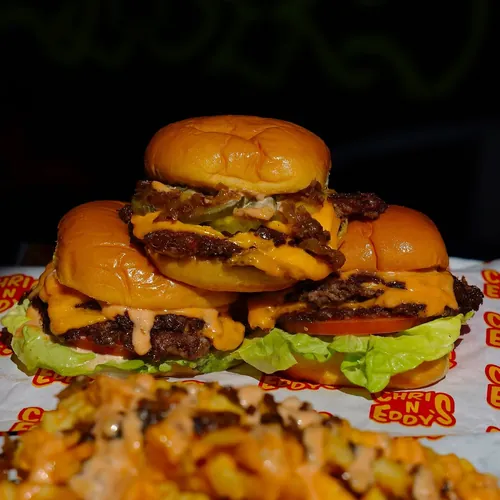 Three sliders stacked on wax paper with loaded fries