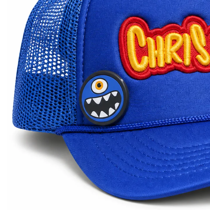 Close-up of the blue Cyclops button pinned at wearer-left, beside the embroidery